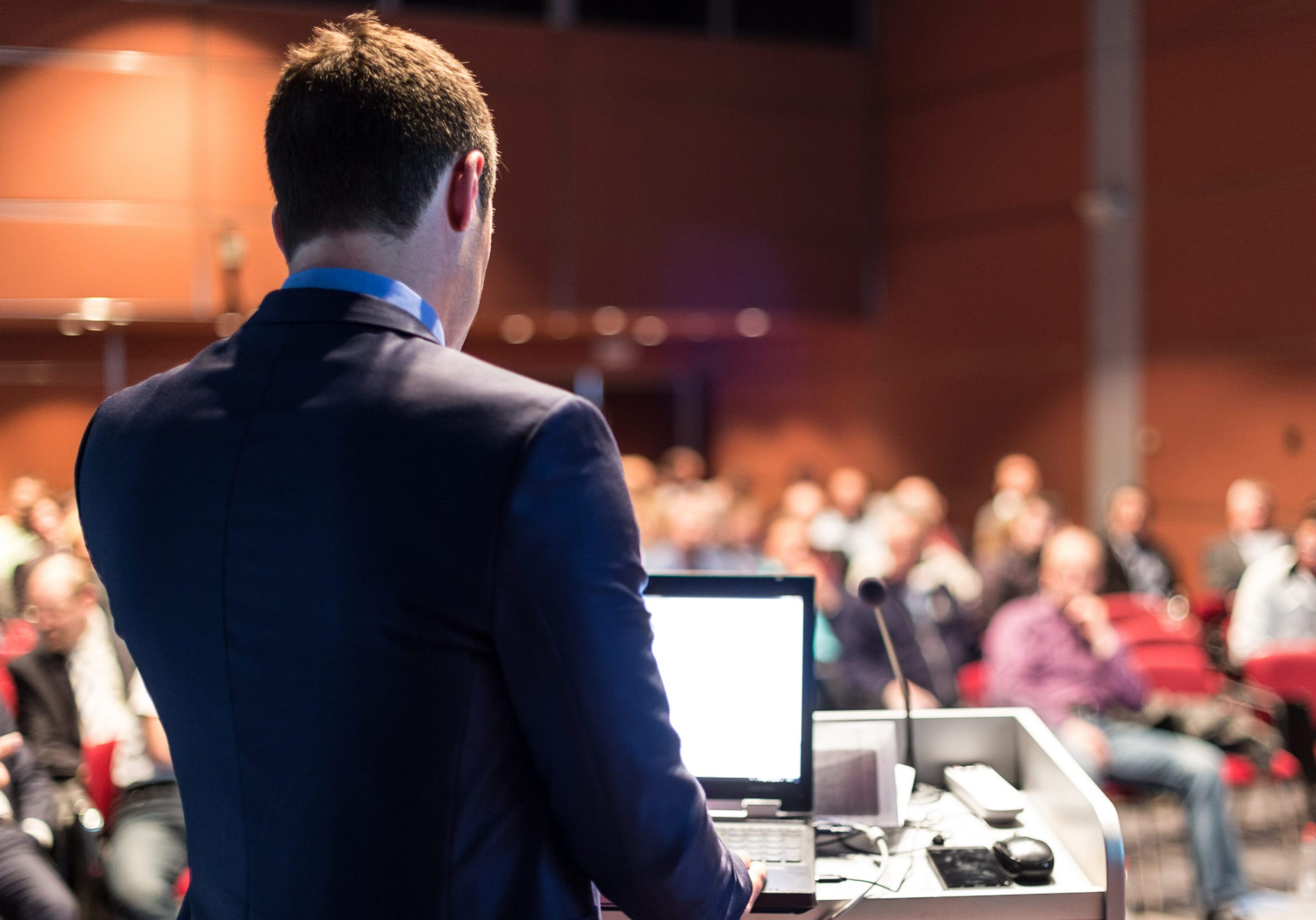 Man at podium, blurred audience